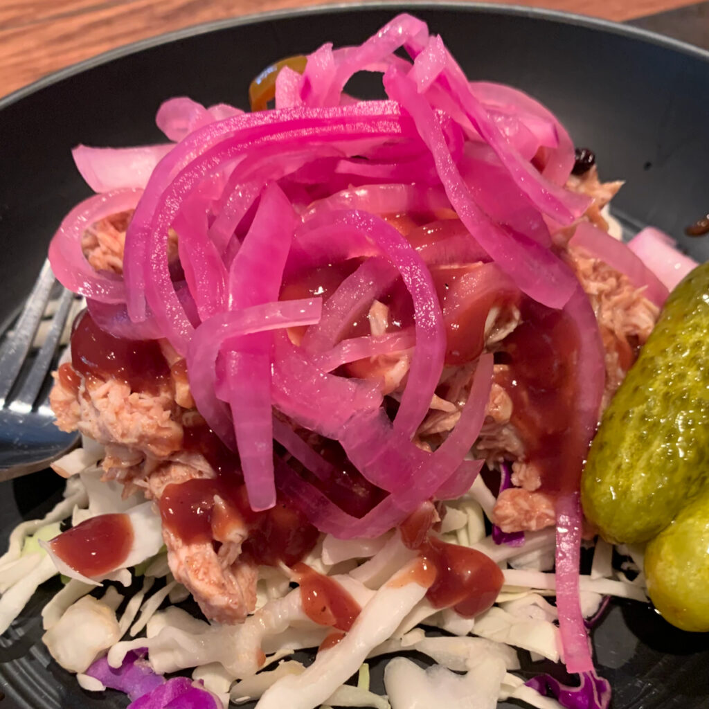 Pickled red onions topped on juicy pulled pork.