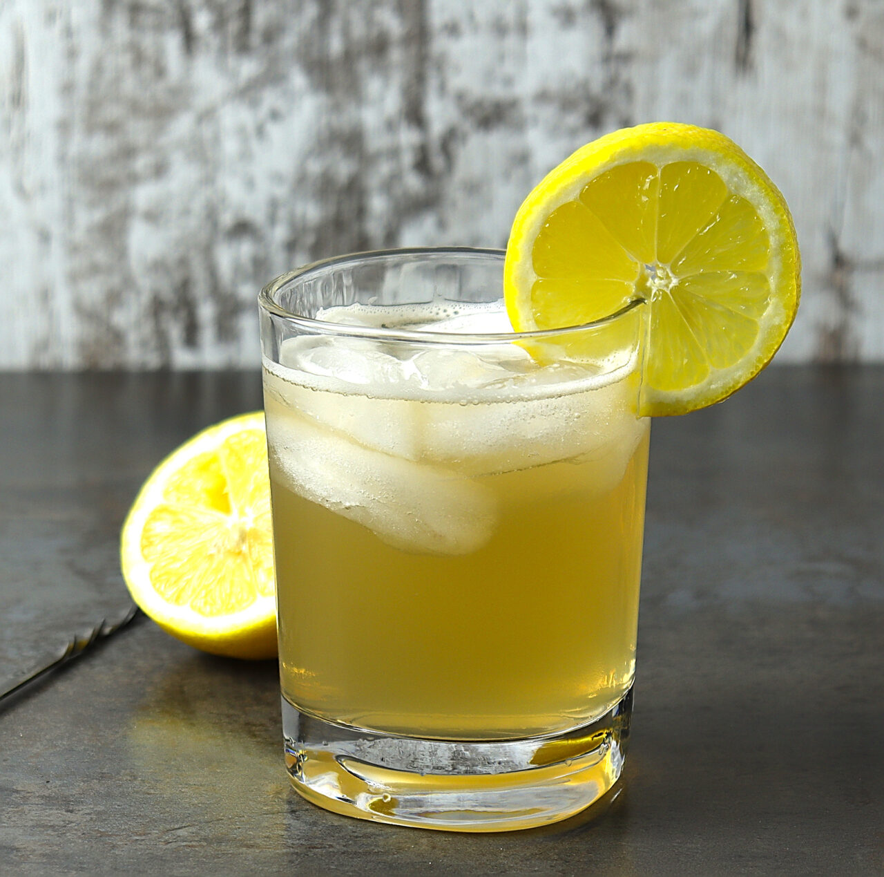 Whiskey lemonade cocktail in a rocks glass, garnished with a slice of lemon.