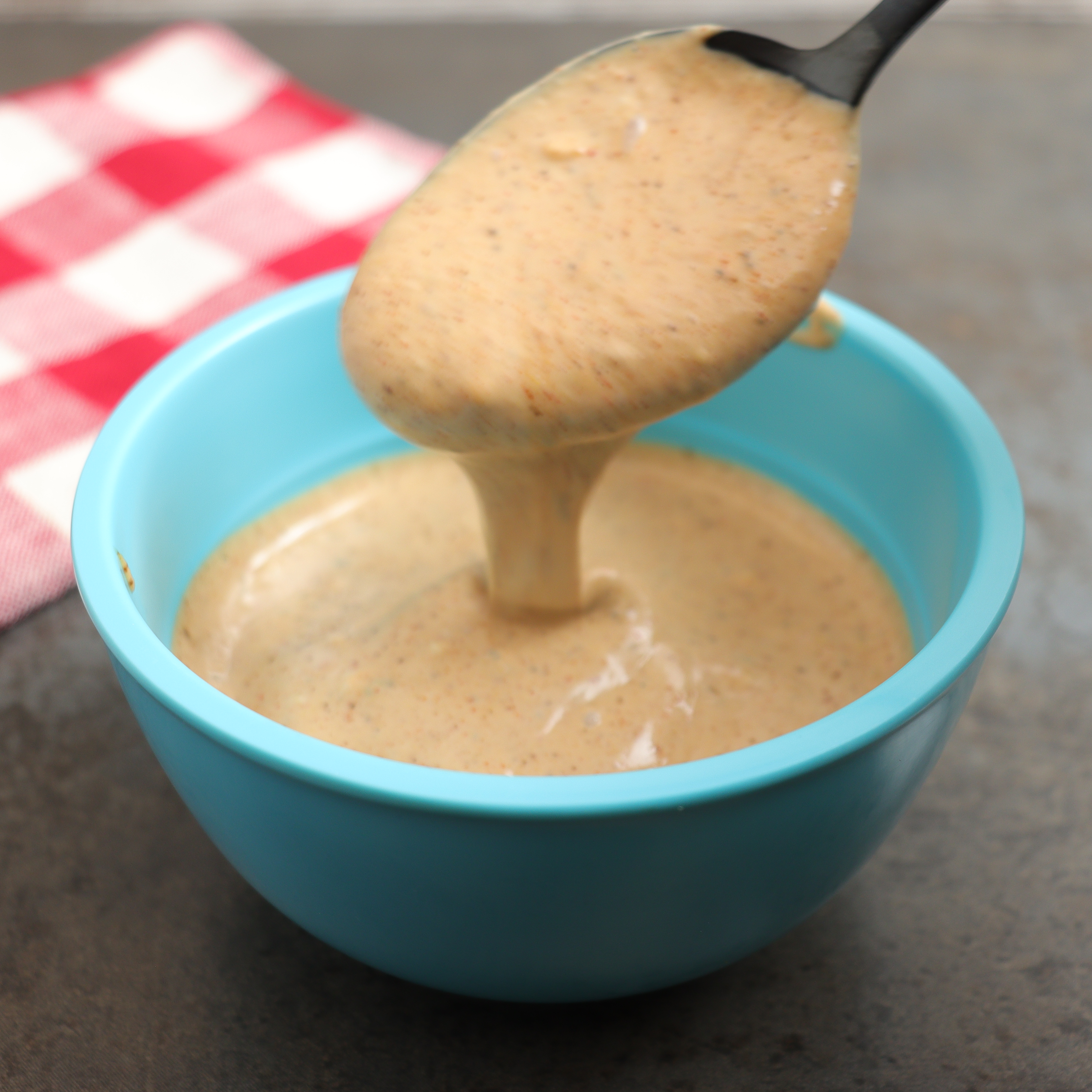 Spooning a burger sauce in a mixing bowl