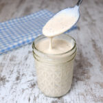 A spoonful of Spicy Alabama White Sauce from a jar.