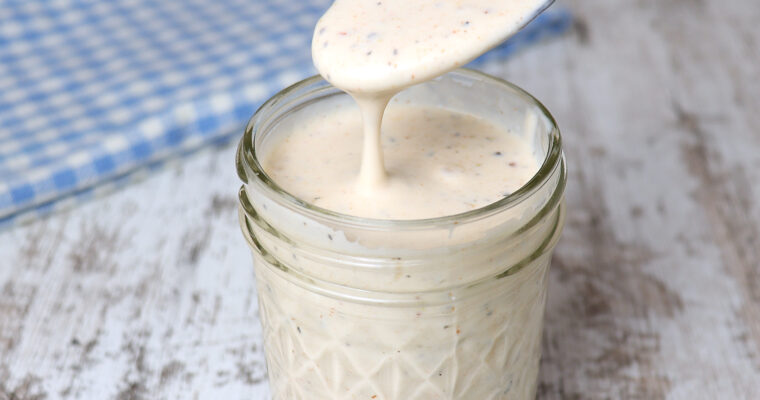 A spoonful of Spicy Alabama White Sauce from a jar.