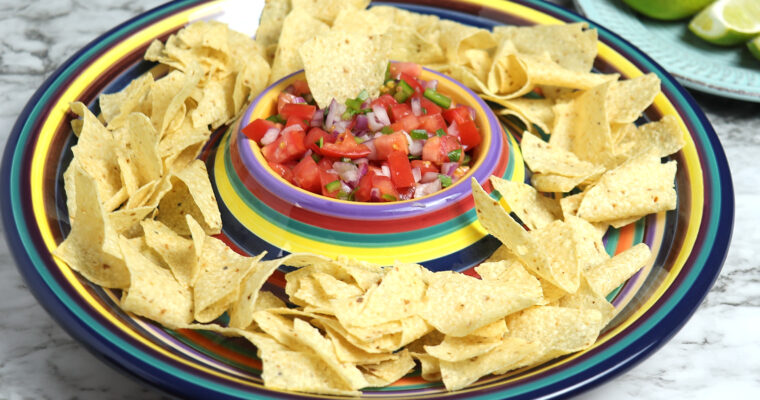 Bowl of fresh Pico de Gallo surrounded with a plate of tortilla chips