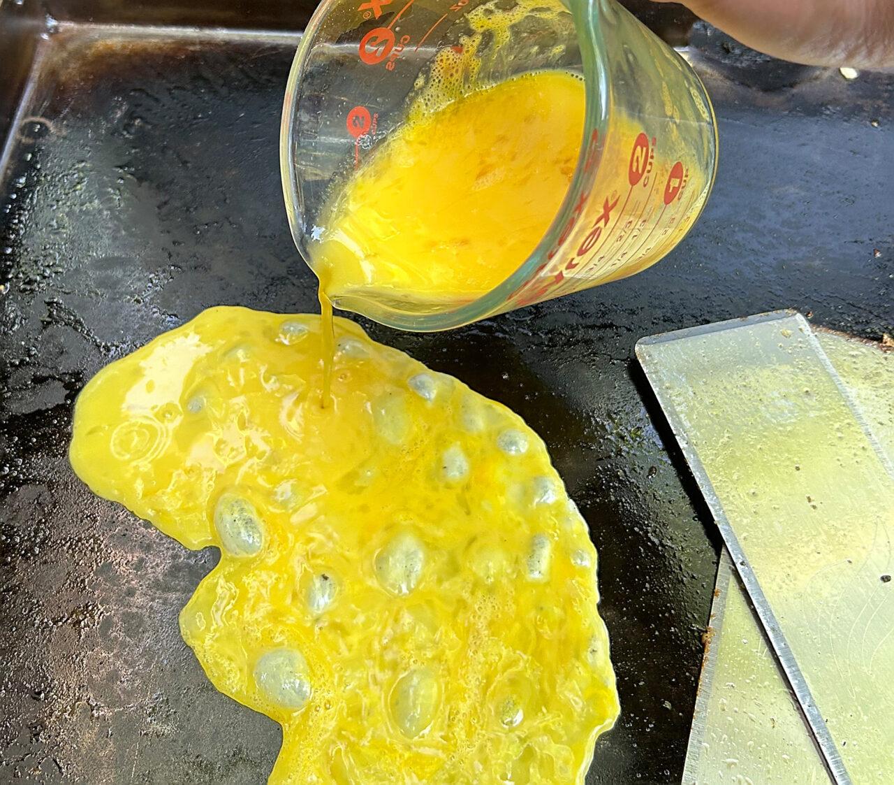 Scrambled eggs on the griddle for a breakfast hash.