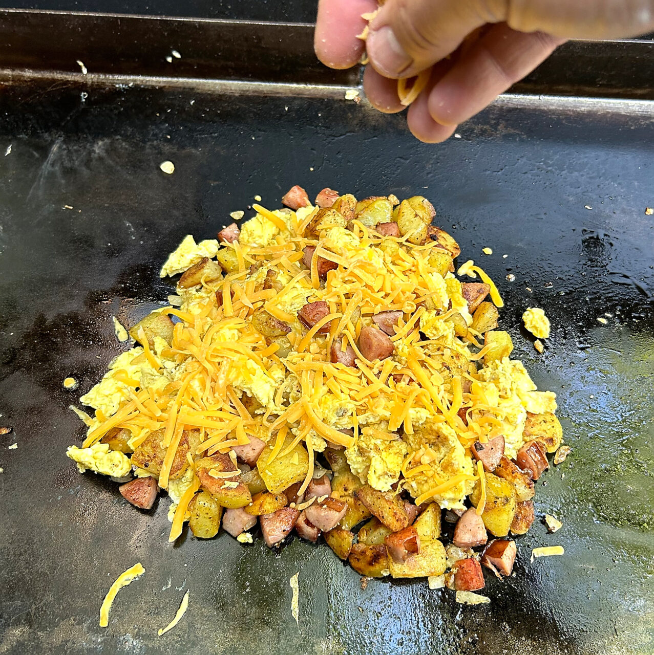 Breakfast hash on the griddle topped with cheddar cheese.