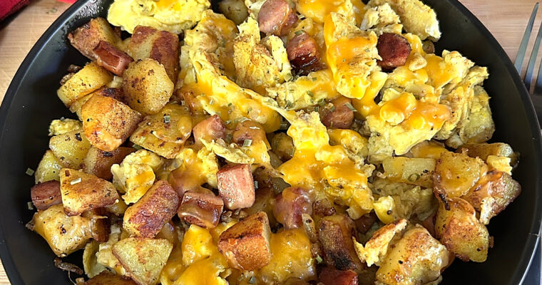 Hearty bowl of breakfast hash with eggs, potatoes, onions, and kielbasa.