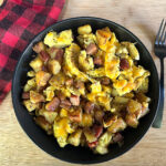 Hearty bowl of breakfast hash with eggs, potatoes, onions, and Kielbasa.