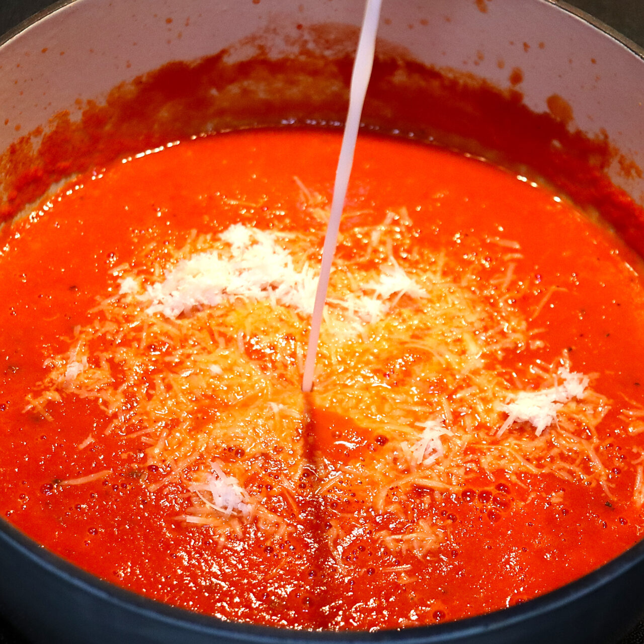 ouring velvety whipping cream and sprinkling freshly grated Parmesan cheese into the simmering tomato soup, elevating its richness and flavor to perfection.