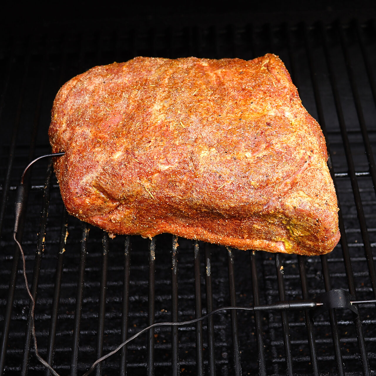 Seasoned pork butt set on the smoker, infused with tantalizing flavors and ready to undergo a low-and-slow smoking process for a mouthwatering result.