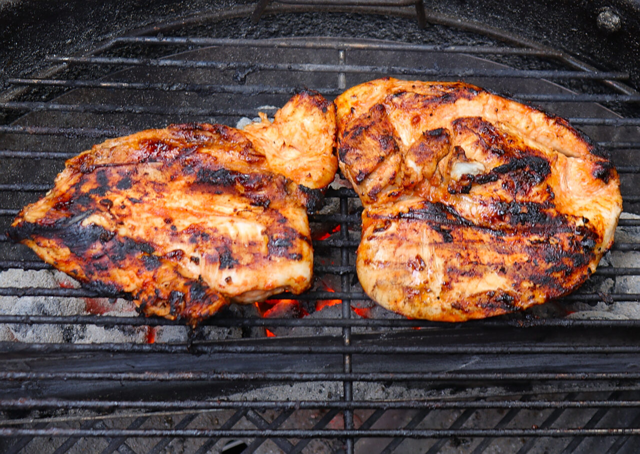 Chicken breasts sizzling on the grill, perfectly charred and infused with smoky flavors during cooking.