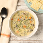 A steaming bowl filled with creamy leftover turkey wild rice soup, showcasing tender chunks of turkey, hearty wild rice, and a luscious, velvety broth.