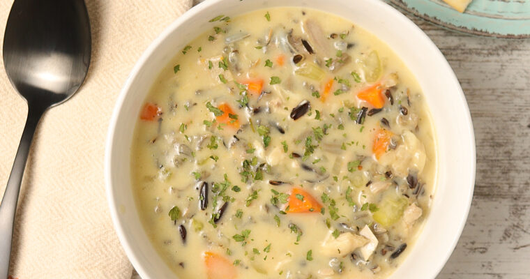 A steaming bowl filled with creamy leftover turkey wild rice soup, showcasing tender chunks of turkey, hearty wild rice, and a luscious, velvety broth.