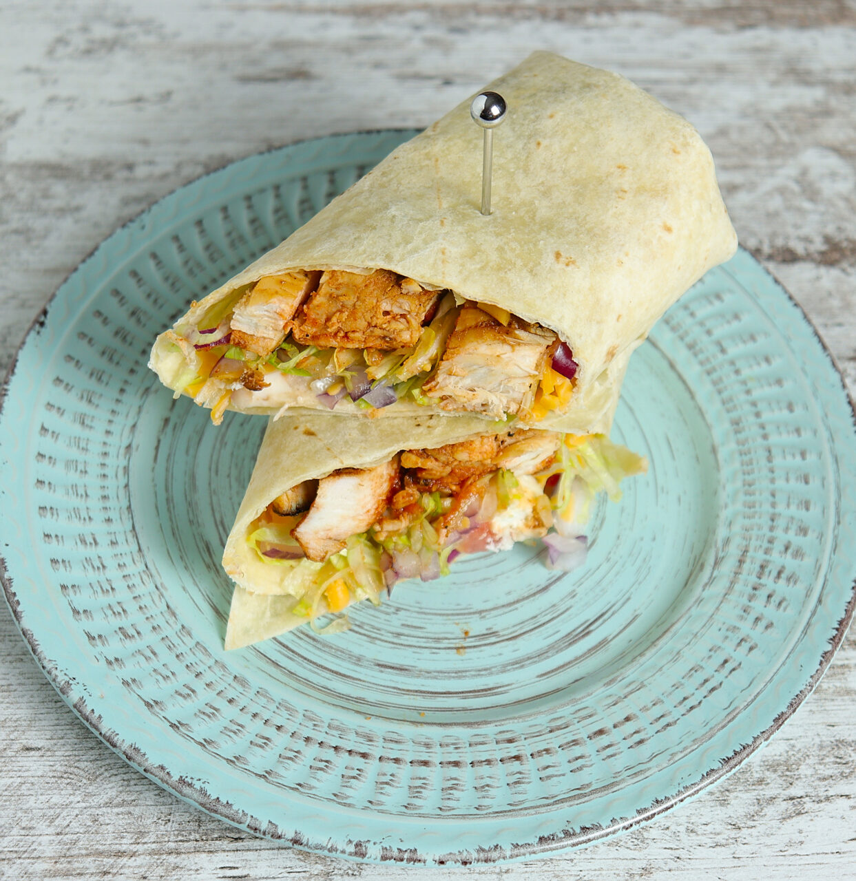 Perfectly sliced Grilled Buffalo Chicken Wrap on a plate, showcasing layers of flavor with juicy chicken, fresh veggies, and a warm tortilla.