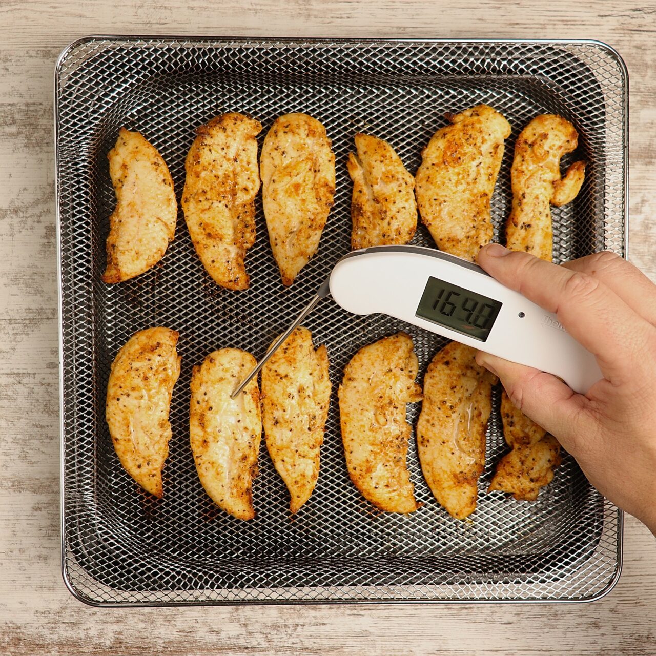 Crispy golden brown chicken tenders reading an internal temperature of at least 165 degrees.
