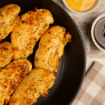 A plate of delicious crispy chicken tenders with a side of dipping sauce.