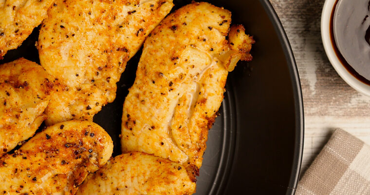 A plate of delicious crispy chicken tenders with a side of dipping sauce.