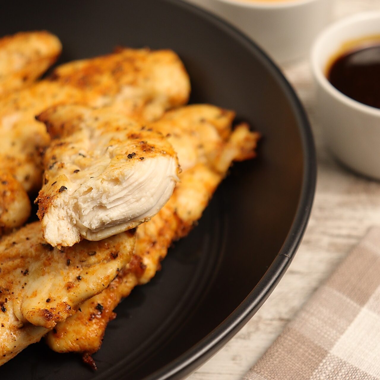 Juicy, flavorful, golden brown chicken tenders with a side of barbecue dipping sauce.