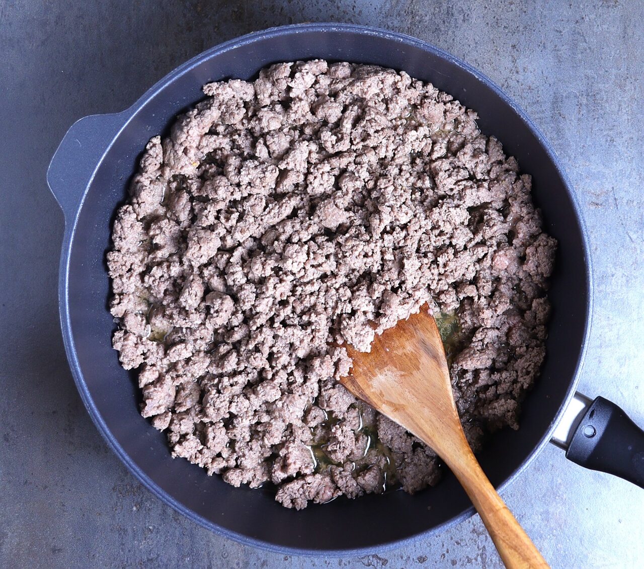 A close-up image of browned ground beef cooking in a skillet. The beef is evenly crumbled and perfectly browned,