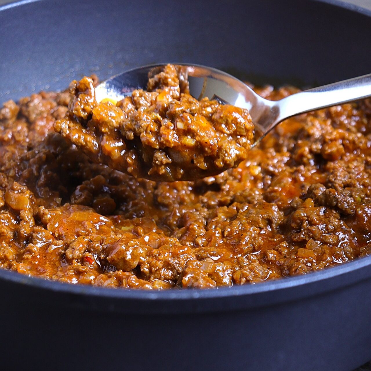 A close-up image of a spoonful of the simmered rich,saucy sloppy joe meat mixture.