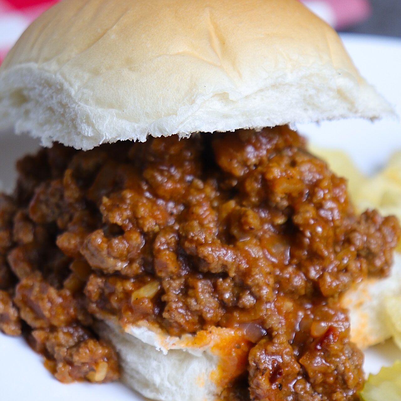 A close-up view of a sloppy Joe sandwich with a soft bun overflowing with flavorful, saucy ground beef filling.