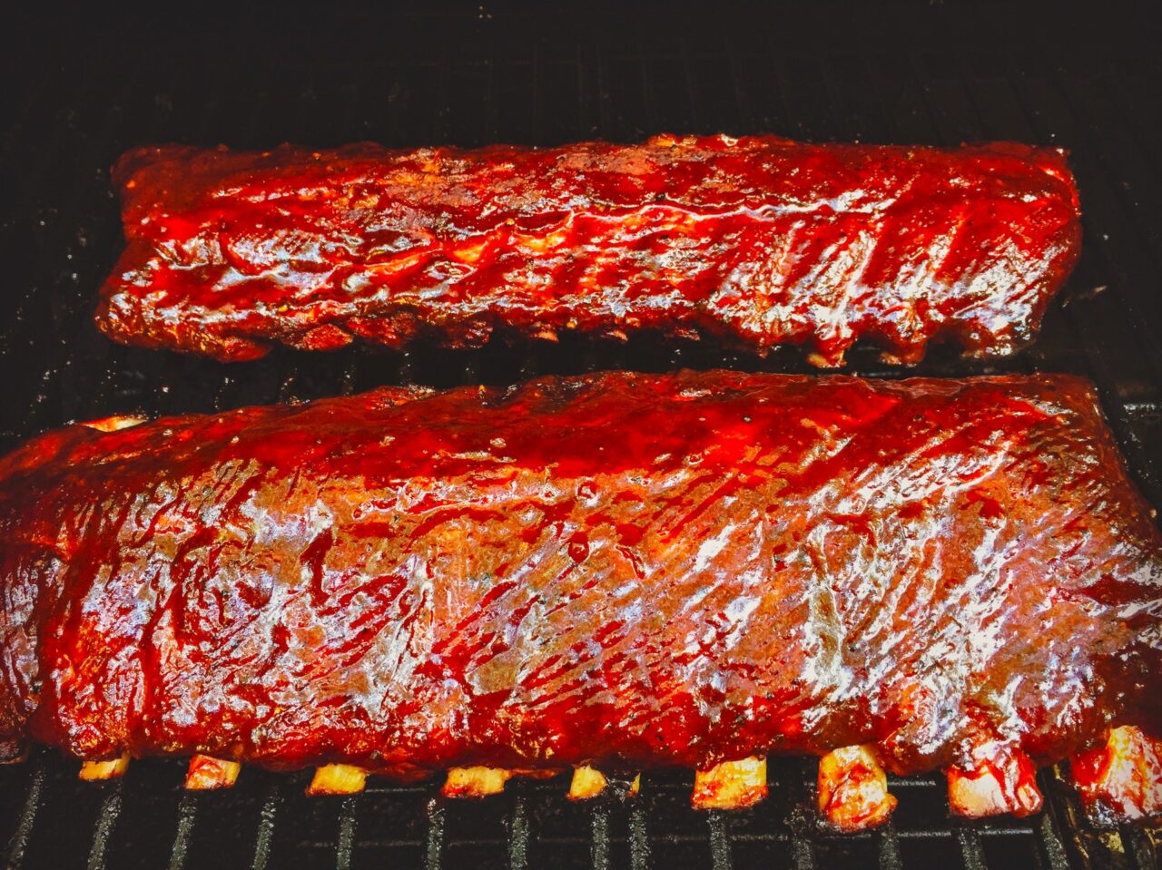 Smoked ribs glazed with homemade BBQ sauce, cooked to perfection on the smoker, showing tender, juicy meat and a delicious caramelized crust.