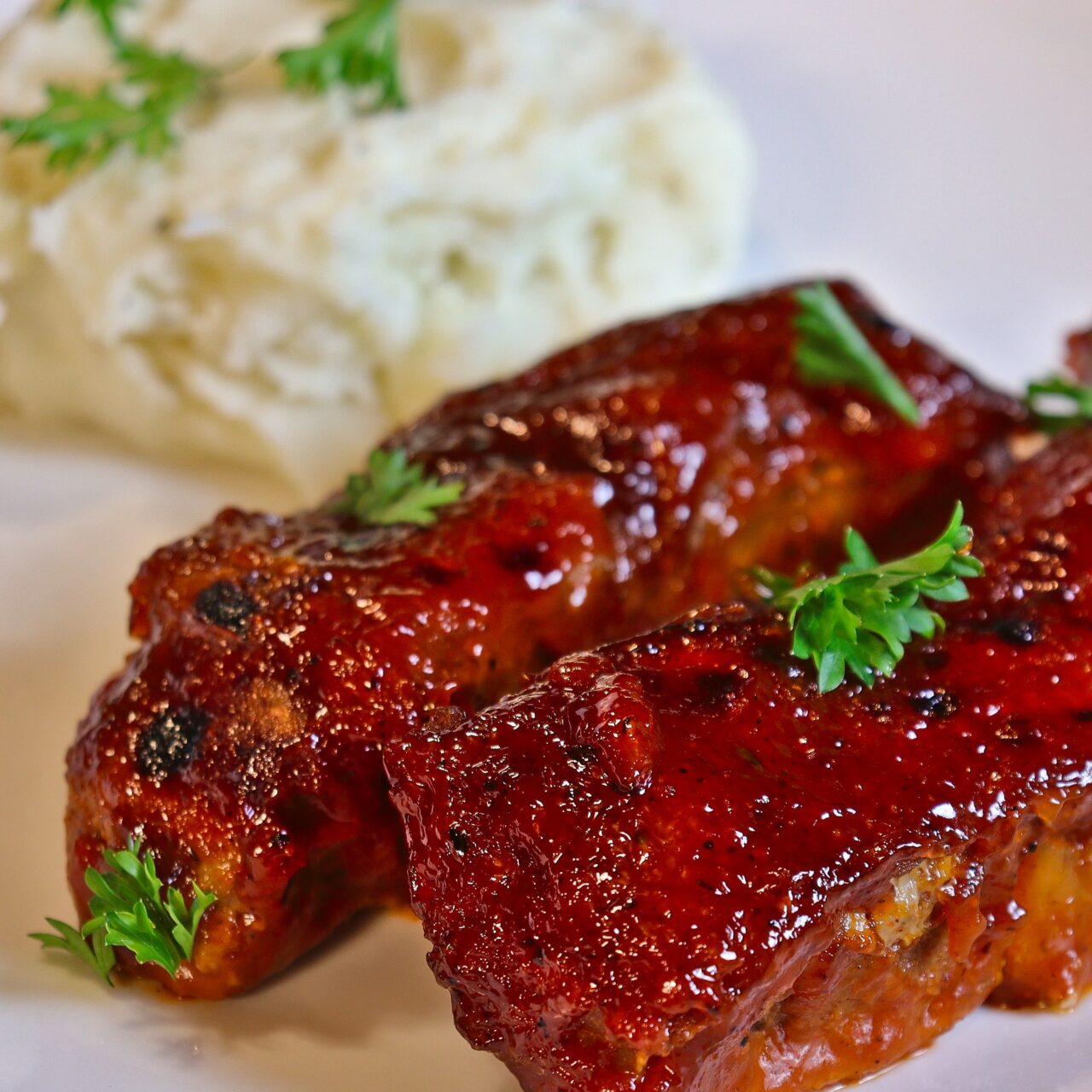 Country-style ribs coated in homemade BBQ sauce, served alongside creamy mashed potatoes for a delicious, comforting meal.